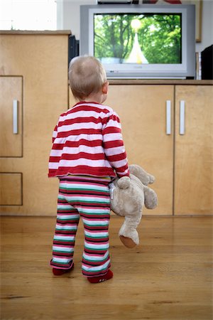 Baby Girl Holding Teddy Bear and Looking at Television, London, England Stock Photo - Premium Royalty-Free, Code: 600-05451176