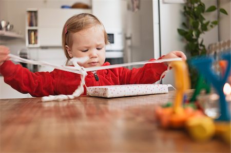 simsearch:600-07734371,k - Little Girl Sitting at Table Unwrapping Gift Foto de stock - Sin royalties Premium, Código: 600-05973081