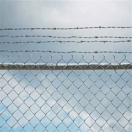 Chain Link Fence and Barbed Wire Foto de stock - Sin royalties Premium, Código: 600-06325427