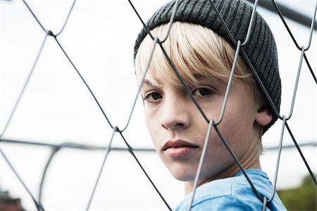 Portrait of Boy Looking Through Chain Link Fence, Mannheim, Baden-Wurttemberg, Germany Stock Photo - Premium Royalty-Free, Code: 600-06382847