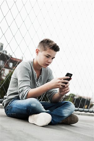 sitting on the ground - Teenage Boy Using Cellular Telephone, Mannheim, Baden-Wurttemberg, Germany Stock Photo - Premium Royalty-Free, Code: 600-06382842