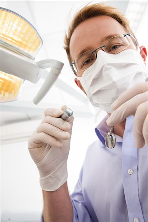 dental office - Dentist wearing Surgical Mask and Holding Dental Instruments looking down, Germany Stock Photo - Premium Royalty-Free, Code: 600-06438918