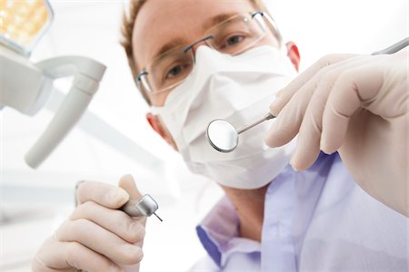 Dentist wearing Surgical Mask and Holding Dental Instruments looking down, Germany Stock Photo - Premium Royalty-Free, Code: 600-06438919