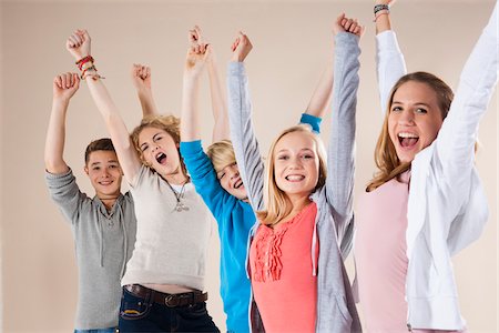 Portrait of Group of Teenage Boys and Girls with Arms in Air, Smiling and Looking at Camera, Studio Shot on White Background Stock Photo - Premium Royalty-Free, Code: 600-06438969