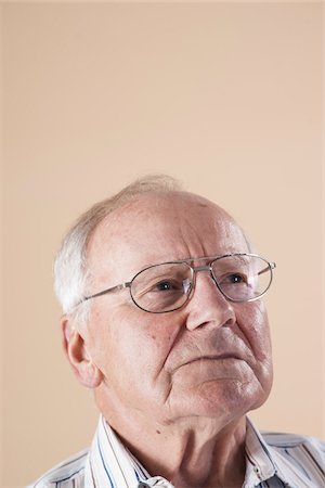 elderly expression - Portrait of Senior Man wearing Aviator Eyeglasses and Looking up into the Distance with Concerned Expression in Studio on Beige Background Stock Photo - Premium Royalty-Free, Code: 600-06438977