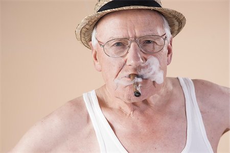 Portrait of Senior Man wearing Undershirt and Straw Hat while Smoking Cigar, Studio Shot on Beige Background Foto de stock - Sin royalties Premium, Código: 600-06438988