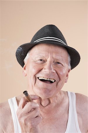 Close-up Portrait of Senior Man wearing Undershirt and Hat while Smoking a Cigar and Smiling, Studio Shot on Beige Background Stockbilder - Premium RF Lizenzfrei, Bildnummer: 600-06438992