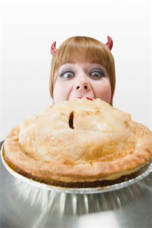 simsearch:600-06431412,k - Young Woman Wearing Devil Horns and Eating a Pie Stock Photo - Premium Royalty-Free, Code: 600-06431362