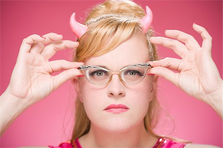 Portrait of Woman Wearing Devil Horns and Vintage Eyeglasses Stock Photo - Premium Royalty-Free, Code: 600-06431403