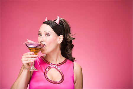 Portrait of Woman Wearing Devil Horns and Drinking a Martini Stock Photo - Premium Royalty-Free, Code: 600-06431433