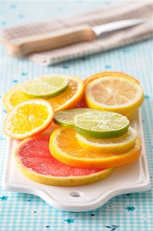 früchte - Close-up of Slices of Citrus Fruits on Cutting Board on Blue Background Stockbilder - Premium RF Lizenzfrei, Bildnummer: 600-06471291