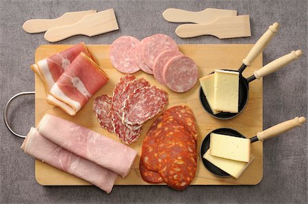 Overhead View of Meats and Cheese for Raclette on Cutting Board on Grey Background, Studio Shot Photographie de stock - Premium Libres de Droits, Code: 600-06486076