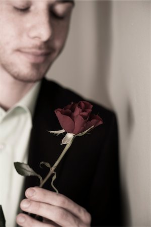 reminiscing photos - Close-up Portrait of Young Man holding Red Rose with Eyes Closed, Studio Shot Stock Photo - Premium Royalty-Free, Code: 600-06486238