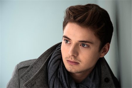 Head and Shoulder Portrait of Young Man wearing Grey Scarf and Jacket, Absorbed in Thought, Studio Shot on Grey Background Stock Photo - Premium Royalty-Free, Code: 600-06486255