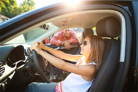 Young girl sitting in driver's seat of car, pretending to be old enough to drive as her smiling father watches on on a sunny summer evening in Portland, Oregon, USA Stock Photo - Premium Royalty-Free, Code: 600-06531446