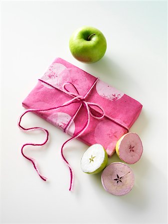 Gift, Craft demonstration of how to use granny smith apples cut in half and dipped in pink and white paint to make wrapping paper Stock Photo - Premium Royalty-Free, Code: 600-06531986