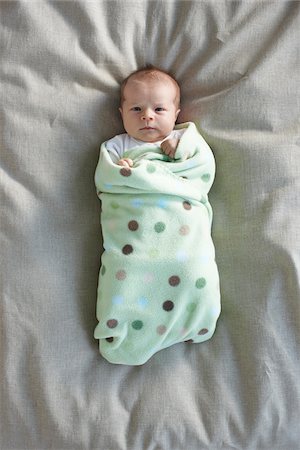 serious little girl - newborn baby girl in a white undershirt sleeping on a bed swaddled in a baby blanket, Ontario, Canada Stock Photo - Premium Royalty-Free, Code: 600-06531990