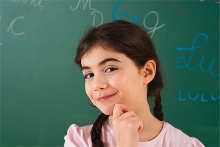 simsearch:600-06543532,k - Girl with Hand on Chin in Front of Chalkboard in Classroom Photographie de stock - Premium Libres de Droits, Code: 600-06543498