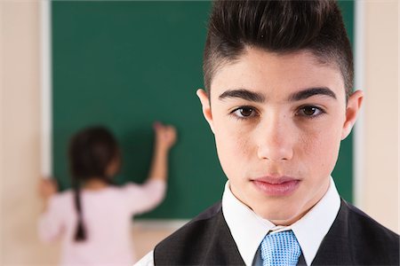 Portrait of Boy in Classroom with Girl in Background at Chalkboard Foto de stock - Sin royalties Premium, Código: 600-06543508