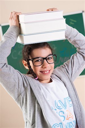 Girl Carrying a Stack of Books on her Head in Classroom Stock Photo - Premium Royalty-Free, Code: 600-06543502