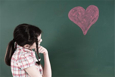 simsearch:600-06543496,k - Girl with Hand on Chin Looking at Heart Drawing on Chalkboard in Classroom Foto de stock - Sin royalties Premium, Código: 600-06543533