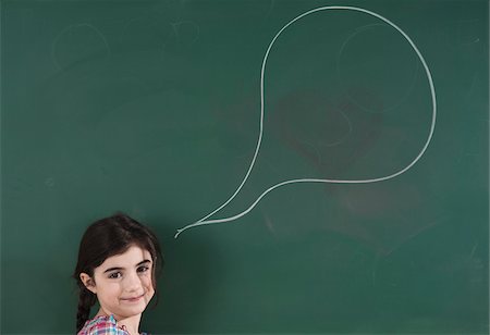 Girl in front of Chalkboard with Speech Bubble in Classroom Stock Photo - Premium Royalty-Free, Code: 600-06543544