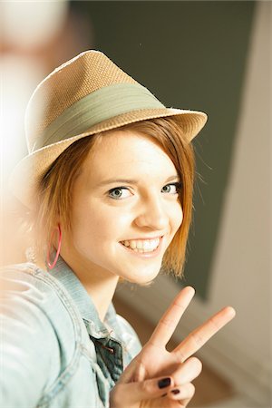 paz - Head and shoulders portrait of teenage girl wearing hat and making a peace sign with her fingers in studio. Foto de stock - Sin royalties Premium, Código: 600-06553550