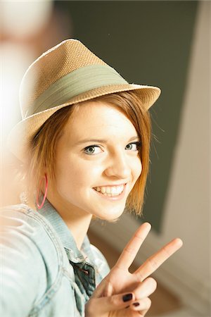 frieden - Head and shoulders portrait of teenage girl wearing hat and making a peace sign with her fingers in studio. Foto de stock - Sin royalties Premium, Código: 600-06553550