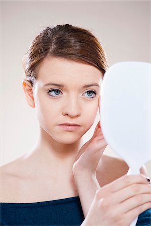 Head and Shoulders Portrait of Teenage Girl Looking in Mirror in Studio Stock Photo - Premium Royalty-Free, Code: 600-06570926