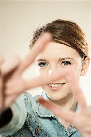 símbolo de paz - Portrait of Teenage Girl Making the Peace Sign with Her Fingers, in Studio Foto de stock - Royalty Free Premium, Número: 600-06570939