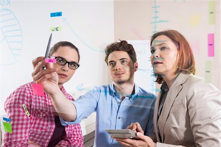 serious woman copy space office - Business People Working in Office Looking at Plans Displayed on a Glass Board Stock Photo - Premium Royalty-Free, Code: 600-06620989