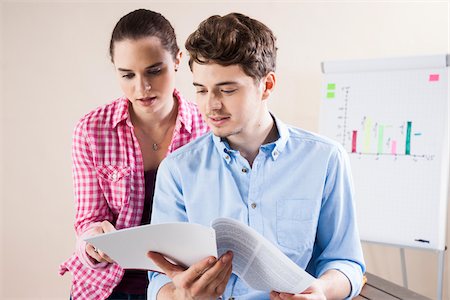 Young Businessman and Young Businesswoman Reading Document in Office Photographie de stock - Premium Libres de Droits, Code: 600-06620992