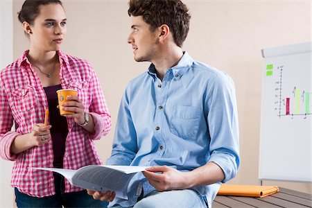 Young Businessman and Young Businesswoman Discussing Document in Office Foto de stock - Sin royalties Premium, Código: 600-06620993