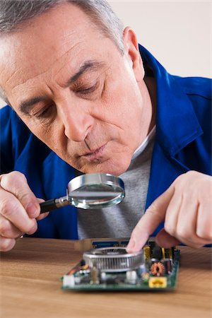 Man Looking at Circuit Board with Magnifying Glass in Studio Stock Photo - Premium Royalty-Free, Code: 600-06645777
