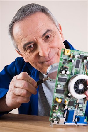 simsearch:600-06787003,k - Portrait of Man Looking at Circuit Board with Magnifying Glass in Studio Foto de stock - Royalty Free Premium, Número: 600-06645778