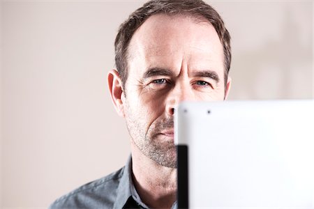 portrait of man staring - Businessman Looking at Tablet Computer, Studio Shot Stock Photo - Premium Royalty-Free, Code: 600-06645894