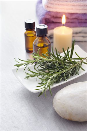 Sprig of rosemary, fresh herbs, candle, towel and bottles of essential oil for aromatherapy Photographie de stock - Premium Libres de Droits, Code: 600-06674995