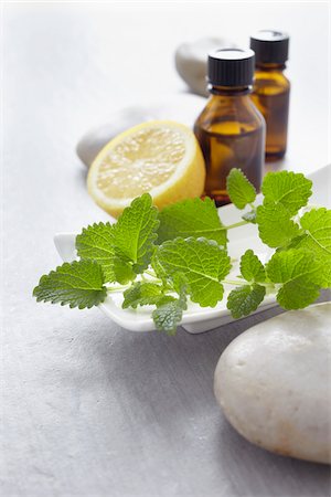 stone (small piece of rock) - Sprig of lemon balm, fresh herbs, lemon and bottles of essential oil for aromatherapy Stock Photo - Premium Royalty-Free, Code: 600-06674993