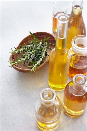 Sprig of rosemary in a bowl, herbs and bottles of oil Stock Photo - Premium Royalty-Free, Code: 600-06675017