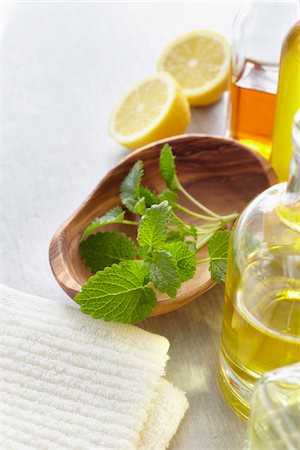 Sprig of lemon balm in a bowl, herbs, towel, a lemon and bottles of essential oil for aromatherapy Stockbilder - Premium RF Lizenzfrei, Bildnummer: 600-06675019