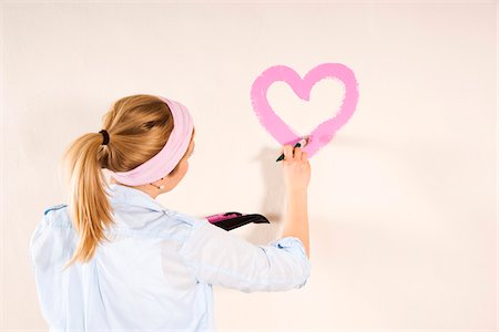 painting - Studio Shot of Young Woman Painting Heart on Wall Stock Photo - Premium Royalty-Free, Code: 600-06671769