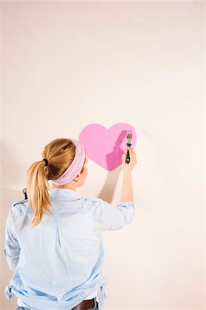 painting - Studio Shot of Young Woman Painting Heart on Wall Stock Photo - Premium Royalty-Free, Code: 600-06671772