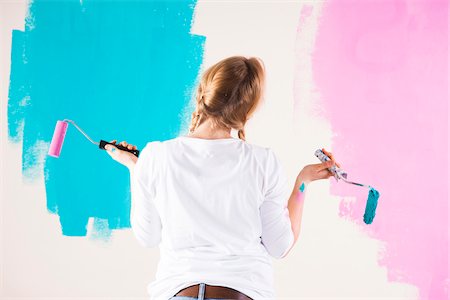 photos on wall - Studio Shot of Young Woman Holding Paint Rollers, Deciding Between Paint Colours Stock Photo - Premium Royalty-Free, Code: 600-06671795