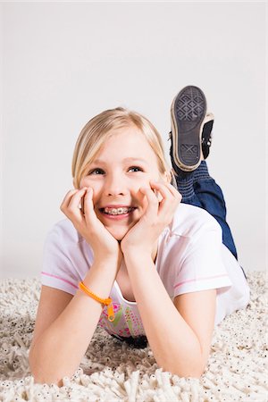 portrait preteen girl - Portrait of Girl Leaning on Hands and Lying on Stomach in Studio Stock Photo - Premium Royalty-Free, Code: 600-06685164