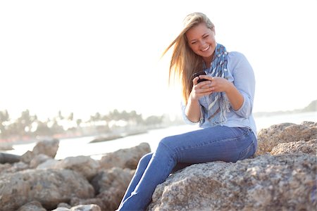 simsearch:600-06531575,k - Young Woman Sitting on Rocks and Texting on Cell Phone at Beach, Jupiter, Palm Beach County, Florida, USA Stock Photo - Premium Royalty-Free, Code: 600-06732633