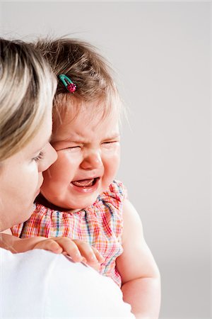 simsearch:600-06752395,k - Portrait of Mother holding Crying Baby Girl, Studio Shot Foto de stock - Royalty Free Premium, Número: 600-06752384