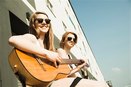 Young women sitting outdoors, hanging out and playing guitar, looking at camera, Mannheim, Germany Photographie de stock - Premium Libres de Droits, Code: 600-06786779