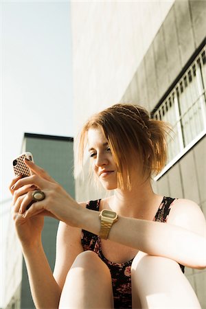 simsearch:600-07311415,k - Teenage girl sitting outdoors and looking at smartphone Photographie de stock - Premium Libres de Droits, Code: 600-06786795