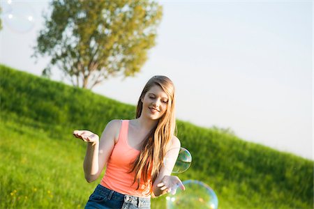 simsearch:700-06826408,k - Young woman standing in field playing with bubbles, Germany Stock Photo - Premium Royalty-Free, Code: 600-06786818