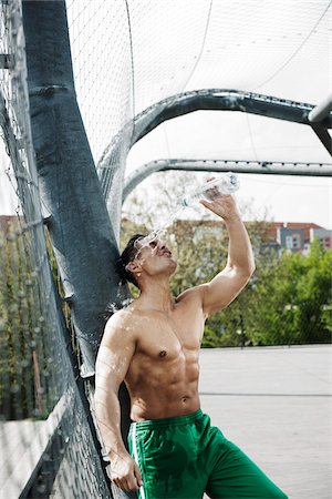 simsearch:600-03333258,k - Mature man standing on outdoor basketball court pouring bottle of water on face, Germany Photographie de stock - Premium Libres de Droits, Code: 600-06786832